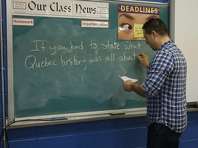 History teacher Sergio Greco writes a question for his students at the John F.Kennedy High School in Montreal, Friday, February 21, 2014. Students in the class were asked to summarize Quebec history in one sentence.