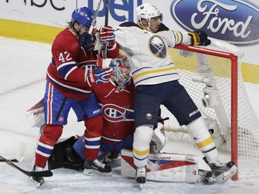 Evander Kane of the Buffalo Sabres leans in on goalie Mike Condon of the Montreal Canadiens as Sven Andrighetto tries to clear him away in the first period of an NHL game at the Bell Centre in Montreal Thursday, March 10, 2016.
