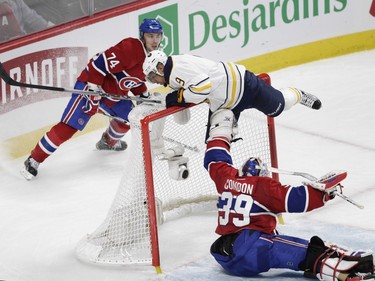 Goalie Mike Condon of the Montreal Canadiens puts his hand up as Evander Kane of the Buffalo Sabres ends up on the top of his net in the second period of an NHL game at the Bell Centre in Montreal Thursday, March 10, 2016. Behind is Alexei Emelin.