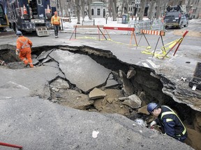 MONTREAL, QUE.: March 10, 2016 -- Workers walk in sinkhole that opened up at the corner of Laval St. and Square Saint-Louis in Montreal Thursday March 10, 2016.  The hole was caused by a water main break.  (John Mahoney / MONTREAL GAZETTE)