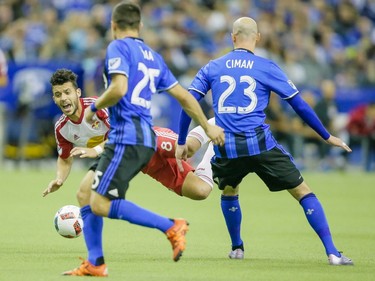 New York Red Bulls midfielder Felipe Martins, rear, falls as he battles for the ball against Montreal Impact defenders Donny Toia, left, and Laurent Ciman, right, during the first half of the Impact's home opener at the Olympic Stadium in Montreal on Saturday, March 12, 2016.