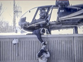 An accomplice tries to help Benjamin Hudon-Barbeau to a helicopter on the roof of the the St-Jérôme detention centre during his escape with fellow inmate Dany Provençal on March 17 2013.