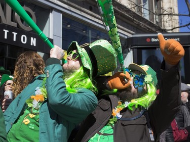 Andrew Thompson, left, and James Wikan blow horns as they take part in the annual St. Patrick's Parade in Montreal on Sunday, March 20, 2016.