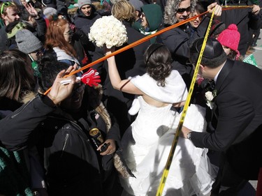 The crowd lifts the barriers and opens a path through the crowd to allow newlyweds Vanessa Dayan and Philippe Mamane to get across Ste-Catherine St. during the annual St. Patrick's Parade in Montreal on Sunday, March 20, 2016.