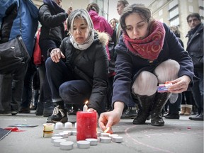 Caroline Pierret, left, and Pauline Froissart light candles during vigil outside the Belgian consulate in Montreal Wednesday March 23, 2016 to commemorate the victims of terror attacks in Brussels.