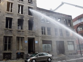 Montreal firemen continue to water down the smouldering remains after an overnight fire on Wellington near Soeurs-Grises Street in Montreal on Friday March 25, 2016.