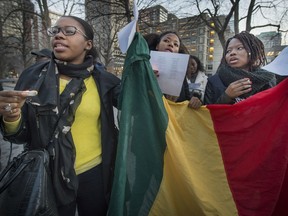 Women sing while holding the Malian flag at Sunday's candlelight vigil at McGill, held to honour victims of terrorism worldwide.