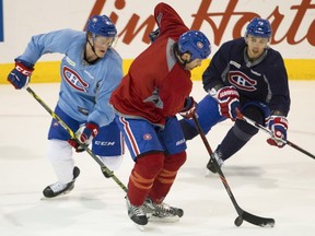 Forward Daniel Carr (left) of the Montreal Canadiens and defenceman Alexei Emelin pursue Mike Brown at the Bell Sports Complex in Brossard near Montreal Monday, March 28, 2016. The team was preparing to face the Detroit Red Wings Tuesday night at the Bell Centre.