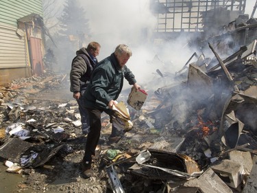 City workers help firefighters remove records and files from a fire, as they battle a blaze at the Ste-Julienne city hall in Ste-Julienne, north of Montreal, Tuesday, March 29, 2016.  The building is a total loss even though the fire station is next door.