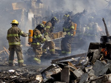 Firefighters and city workers remove records and files from a fire, as they battle a blaze at the Ste-Julienne city hall in Ste-Julienne, north of Montreal, Tuesday, March 29, 2016.  The building is a total loss even though the fire station is next door.