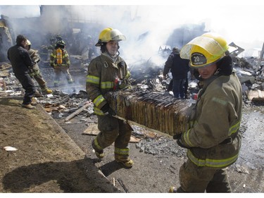 Firefighters and city workers remove records and files from a fire, as they battle a blaze at the Ste-Julienne city hall in Ste-Julienne, north of Montreal, Tuesday, March 29, 2016.  The building is a total loss even though the fire station is next door.