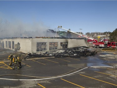 Firefighters battle a blaze at Ste-Julienne city hall north of Montreal March 29, 2016. The building is a total loss even though the fire station is next door.