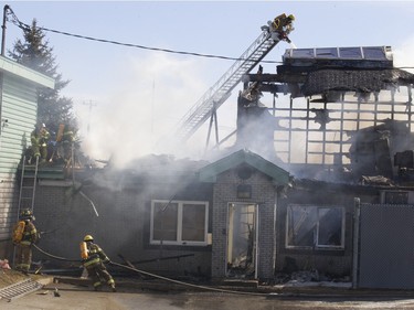 Firefighters battle a blaze at Ste-Julienne city hall north of Montreal March 29, 2016. The building is a total loss even though the fire station is next door.