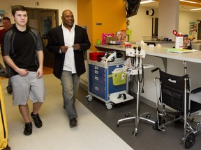 Former Montreal Expos Tim Raines, right, walks with Matthew Tucker as they visit a new physiotherapy room at the Montreal Children's Hospital in Montreal on Thursday March 31, 2016. The Toronto Blue Jays donated a the physiotherapy room which would benefit patients like Tucker who suffered injuries playing baseball at the age of 15.