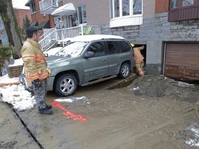 A firefighter walks down a driveway covered with mud, after flooding from a water main break on Cavendish Blvd. between Fielding and Chester Aves. March 8, 2016.