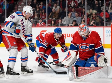 Goaltender Mike Condon of the Montreal Canadiens and teammate Alexei Emelin #74 try to defend the puck against J.T. Miller #10 of the New York Rangers during the NHL game at the Bell Centre on March 26, 2016, in Montreal.