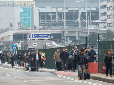 People walk away from Brussels airport after explosions rocked the facility in Brussels, Belgium Tuesday March 22, 2016.   Explosions rocked the Brussels airport and the subway system Tuesday, just days after the main suspect in the November Paris attacks was arrested in the city, police said.