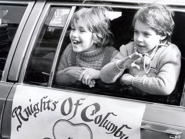 Two children wave from inside a car used in the parade by the Knights of Columbus organization.