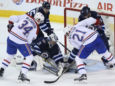 Winnipeg Jets goaltender Ondrej Pavelec looks for a loose puck as the Montreal Canadiens swarm his goal in Winnipeg on Sat., March 5, 2016.