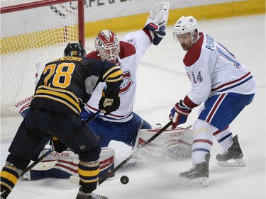 Buffalo Sabres' Zemgus Girgensons (28) shoots the puck as Montreal Canadiens' Ben Scrivens, center, Tomas Plekanec (14) defend during the overtime session of an NHL hockey game, Wednesday, March 16, 2016, in Buffalo, N.Y.  Montreal won 3-2.