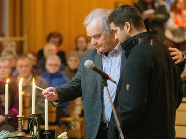 Rodrique Brillant, left, husband of Martine Lapierre, and their son Sergei, light a candle during a commemorative mass for the victims of the March 29 airplane crash at Sainte-Madeleine de Havre-aux-Maisons church in Les Iles de la Madeleine on Tuesday, April 5, 2016.