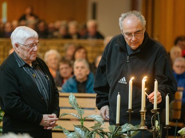 Denis Frechette, husband of Laure Lapierre, lights a candle next to priest Rejean Coulombe, left, during a commemorative mass for the victims of the March 29 airplane crash at Sainte-Madeleine de Havre-aux-Maisons church in Les Iles de la Madeleine on Tuesday, April 5, 2016.