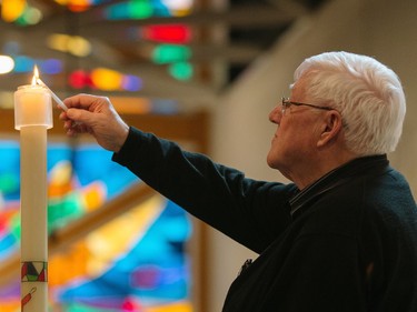 Priest Rejean Coulombe lights a candle during a commemorative mass for the victims of the March 29 airplane crash at Sainte-Madeleine de Havre-aux-Maisons church in Les Iles de la Madeleine on Tuesday, April 5, 2016.