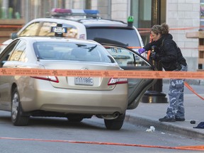 A Montreal police officer takes photographs of a taxi cab during an investigation of a shooting on St-Laurent Blvd. near Roy St. E. in Montreal, Monday April 25, 2016.  The suspect escaped on foot, police believe.