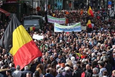 People hold the Belgium national flag and banners reading as they take part in the peaceful march "#Tousensemble - #Sameneen" against terrorism and hate in the city centre of Brussels on April 17, 2016.