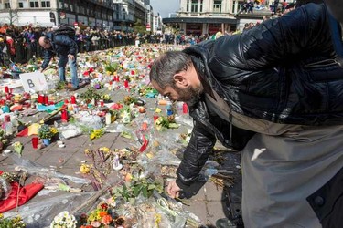 A man deposit some flowers at the makeshift memorial in the stock exchange square in Brussels during the peaceful march "#Tousensemble - #Sameneen" against terrorism and hate on April 17, 2016.