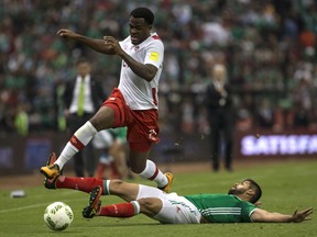 Canada's Cyle Larin, top, fights for the ball with Mexico's Nestor Araujo during a World Cup qualifying soccer match in Mexico City, on March  29, 2016.