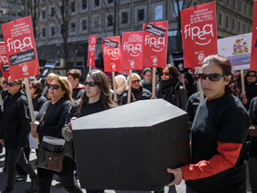 Protesters carry a symbolic coffin as they take part in a small demonstration with a "funeral" theme to denounce funding cuts to Quebec's public daycare system in Montreal on Saturday, April 23, 2016.