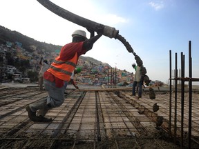 A Haitian worker pours cement for an office building under construction in Petion Ville, Haiti.