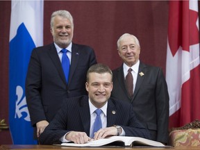 Luc Fortin, centre, is sworn in Thursday, January 28, 2016 at the legislature in Quebec City. Quebec Premier Philippe Couillard, left, and Lt. Governor J. Michel Doyon stand behind.