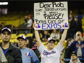 A baseball fan holds a sign asking to bring back the Montreal Expos before the second exhibition game between the Toronto Blue Jays and the Boston Red Sox at the Olympic Stadium in Montreal on Saturday, April 2, 2016.