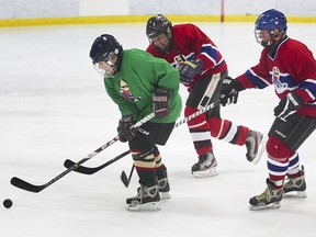 A player from the Vachon team, in green, and players from Châteauguay fight for control of the puck during 80-and-older game at the Lassonde-Tyler Friendly Tournament at the Gaétan Boucher Arena in St-Hubert