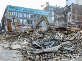 An excavator clears debris from the site of a building that collapsed while being demolished at the corner of St-Catherine St. and St-André St. in Montreal Tuesday April 26, 2016.
