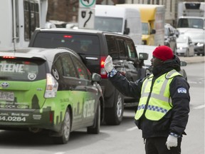 A Montreal police officer directs traffic at the intersection of Décarie Blvd. and Côte-St-Luc Rd. in Montreal, Wednesday April 6, 2016.  The closure of the Sherbrooke St. exit off the northbound Décarie Expressway due to the Turcot reconstruction project is creating traffic headaches in the area.