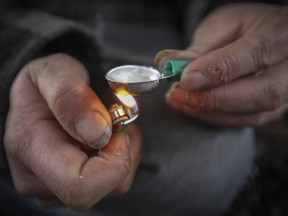 MONTREAL, QUE.: November 25, 2014 -- Drug addict Denis heats a spoon full of morphine-hydrochloride in Viger Square in Montreal Tuesday November 25, 2014. He shared the $15 cost of a hit with a fellow addict Martin Pare. (John Mahoney / MONTREAL GAZETTE)