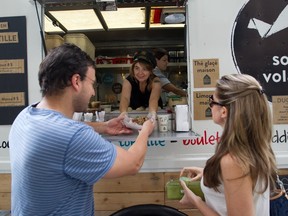 Ô Soeurs Volantes co-owner Julie Gilbert (behind her is other co-owner Stéphanie Broussaud) serves customers Edward Hoyeck and Colette Martin from their food truck in Montreal Monday, September 2, 2013.