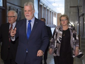Quebec Premier Philippe Couillard, centre, walks to a party caucus meeting with Chicoutimi byelection candidate Francine T. Gobeil, right, Tuesday, March 8, 2016, at the legislature in Quebec City.