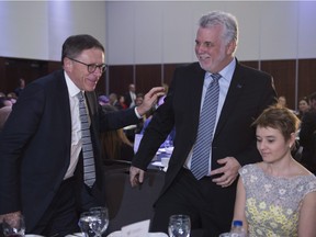 Quebec Premier Philippe Couillard, right, gets a pat on the shoulder from Lévis Mayor Gilles Lehouillier after a speech at the local chamber of commerce luncheon, Friday, April 15, 2016 in Lévis, near Quebec City.