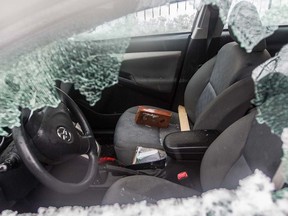 A Montreal police officer surveys a vandalized car on Pascal St. in Montreal North, April 7, 2016. A small riot following a peaceful demonstration resulted in torched and vandalized cars, vandalized buildings including a police station.