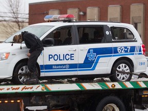 A tow truck operator prepares a vandalized police car outside Montreal police Station 39 in Montreal North, April 7, 2016. A small riot following a peaceful demonstration resulted in torched cars, vandalized buildings including the police station.