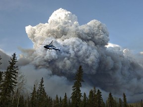 A helicopter flies past a wildfire in Fort McMurray, Alta., on Wednesday May 4, 2016. The wildfire has already torched 1,600 structures in the evacuated oil hub of Fort McMurray.