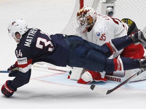 Auston Matthews of the United States, bottom, falls as he attacks the net of goalkeeper Kevin Lalande of Belarus during the Hockey World Championships Group B match in St.Petersburg, Russia, Saturday, May 7, 2016.