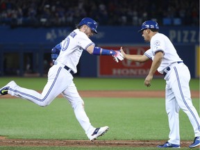 Josh Donaldson #20 of the Toronto Blue Jays is congratulated by third base coach Luis Rivera #4 after hitting a two-run home run in the eighth inning during MLB game action against the Boston Red Sox on May 27, 2016, at Rogers Centre in Toronto.