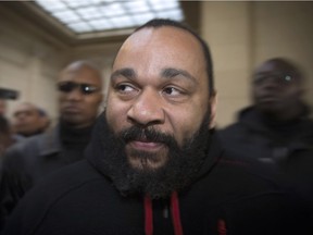 French controversial humorist Dieudonne Mbala Mbala arrives for a trial at the Paris courthouse on December 13, 2013 on the charges of defamation, insults, incentive to hate and discrimination. On November 28, 2013 in Paris, Dieudonne was already sentenced, during another and different trial, to pay a 28.000 euros fine for defamation, insults, incentive to hate and discrimination for remarks and a song broadcasted in two videos on Internet.
