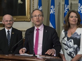 Quebec Municipal Affairs Minister Martin Coiteux, centre, announces a new government plan to reduce costs to municipalities as Quebec Municipalities Union (UMQ) president Suzanne Roy, right, and Richard Lehoux, president of the Federation Quebecois des Municipalités (FQM) at a news conference, Wednesday, May 11, 2016 at the legislature in Quebec City.