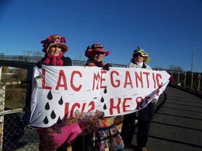 Montreal, Oct. 30, 2014, Montreal Raging Grannies hang banner "Lac Megantic Ici? Here?" from Sources Blvd. overpass on Hwy. 20. Pictured from left to right, Helen Van Veeren, Joan Hadrill and Sheila Laursen. The morning rush hour event was designed to alert eastbound motorists to the increasing number of oil tankers moving by rail through the West Island. Photo Credit: Elizabeth Vezina.